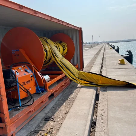 Marine salvage operation showing a partially sunken vessel alongside a quay during recovery operations using cranes and lifting equipment.