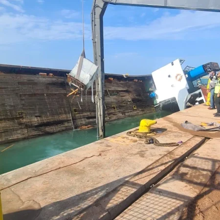 Marine salvage operation showing vessel recovery activities alongside a quay using cranes, lifting equipment, and safety controls.