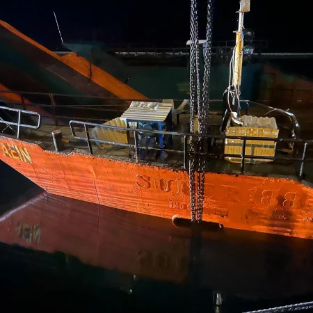 Marine salvage operation showing vessel recovery activities alongside a quay using cranes, lifting equipment, and safety controls.