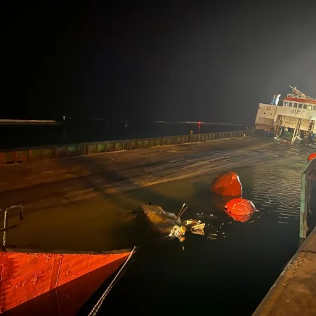 Marine salvage operation showing vessel recovery activities alongside a quay using cranes, lifting equipment, and safety controls.