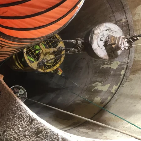 Confined space mechanical works at PS30 showing core drilling and installation of 1000mm diameter air recirculation duct within reinforced concrete shaft.