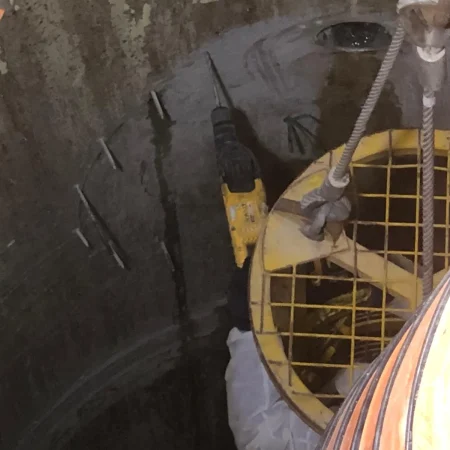 Confined space mechanical works at PS30 showing core drilling and installation of 1000mm diameter air recirculation duct within reinforced concrete shaft.